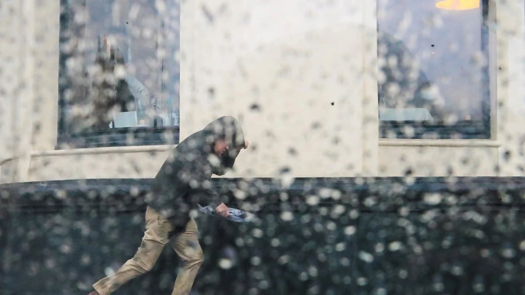 Imagen de archivo de un hombre intentando resguardarse de una tormenta