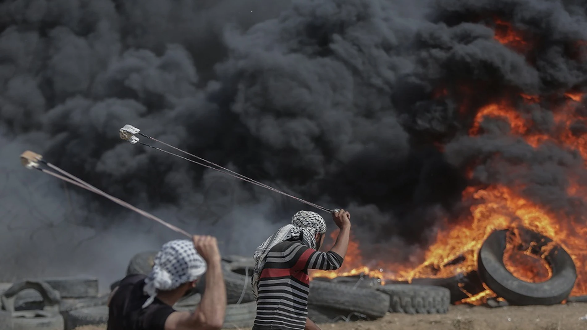 Dos palestinos lanzan piedras en una protesta en Gaza