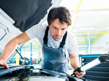 Mecánico reparando un coche en el taller Mecánico reparando un coche en el taller