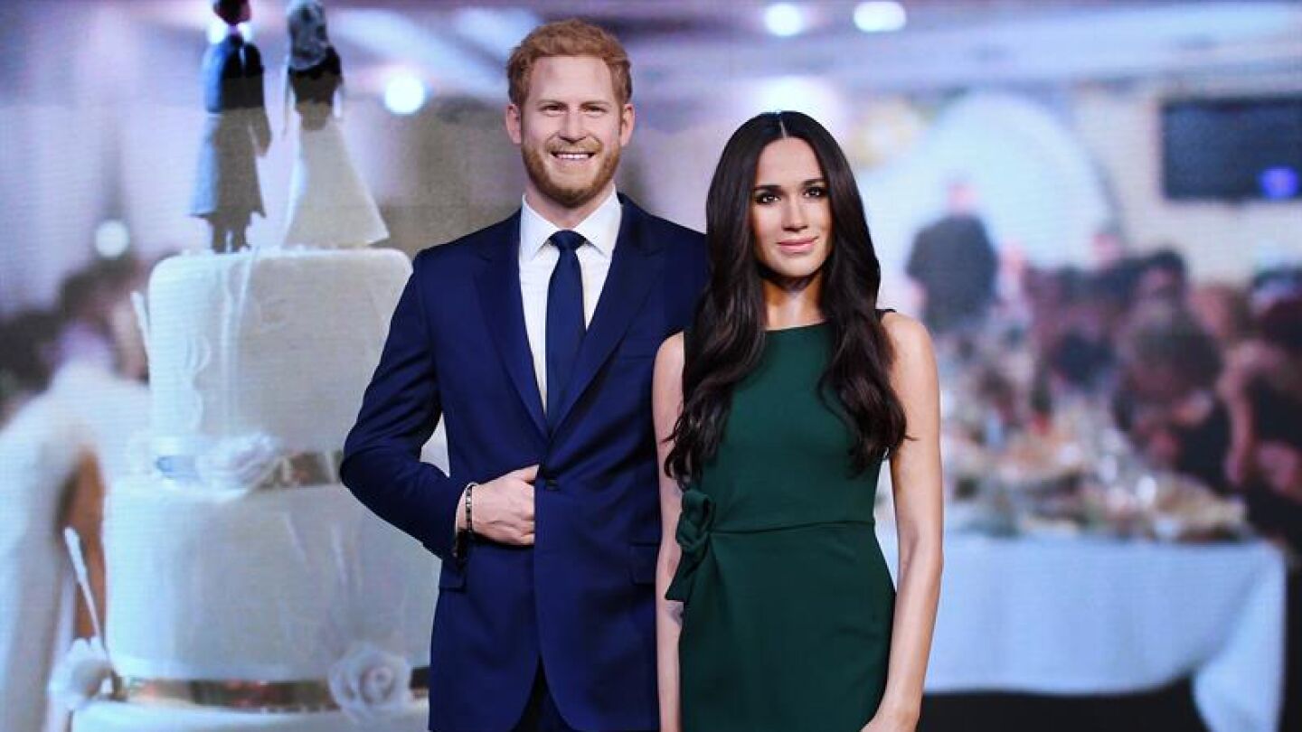 Dos j&oacute;venes observan de cerca la nueva r&eacute;plica en cera de Meghan Markle (2d), colocada junto a la de su futuro marido, el pr&iacute;ncipe Enrique, durante su presentaci&oacute;n en el museo de cera de Madame Tussaud de Londres (Archivo)