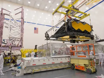 Sala blanca de las instalaciones de Northrup Grumman donde se está extrayendo de un cubículo la parte óptica del JWST para someterla a pruebas Sala blanca de las instalaciones de Northrup Grumman donde se está extrayendo de un cubículo la parte óptica del JWST para someterla a pruebas
