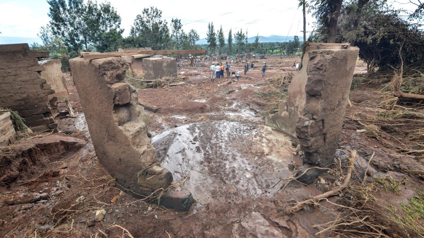 Varias personas pasan entre las casas destruidas por las aguas tras destruirse la presa 