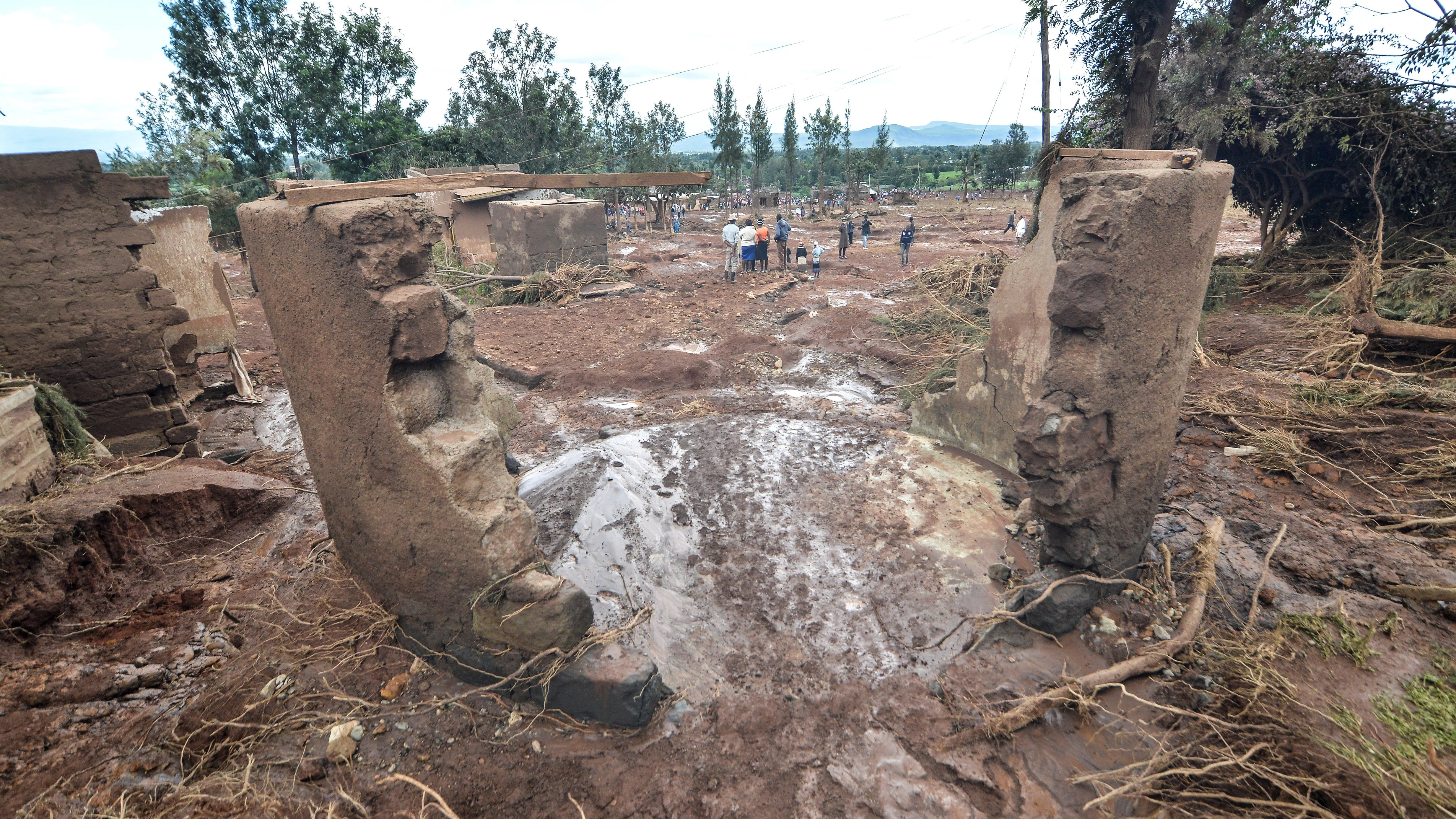 Varias personas pasan entre las casas destruidas por las aguas tras destruirse la presa 