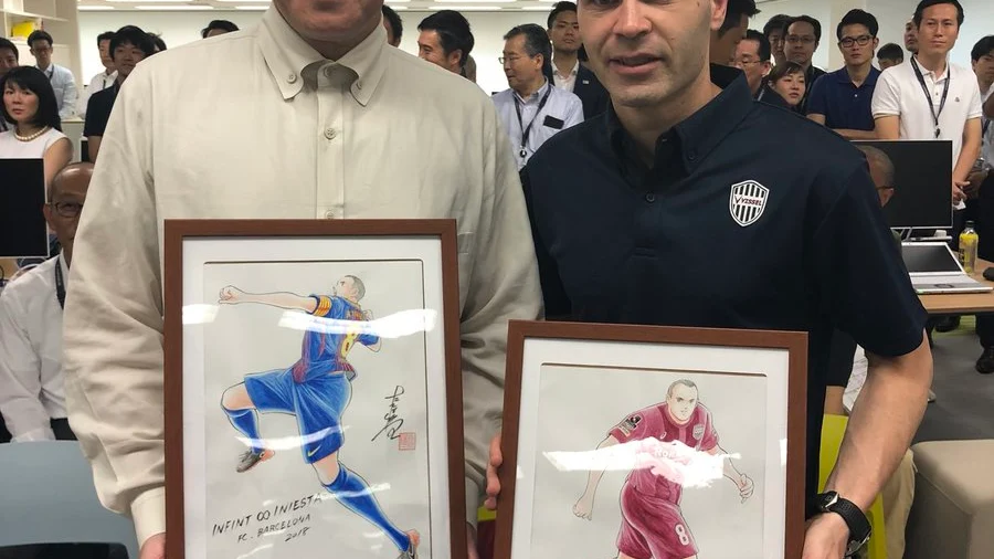 Takahashi posa con Iniesta y sus dos dibujos