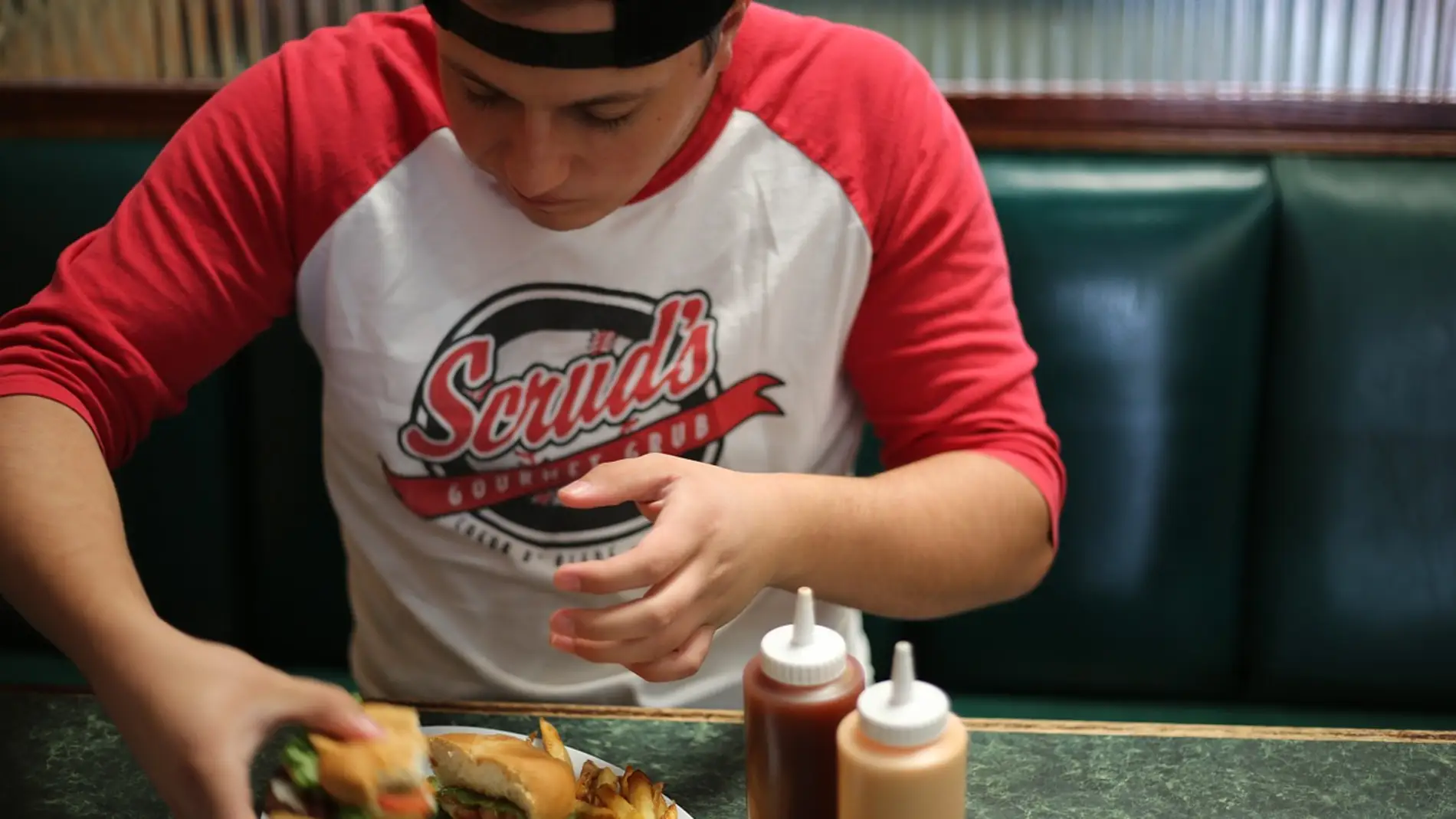 adolescente comiendo una hamburguesa