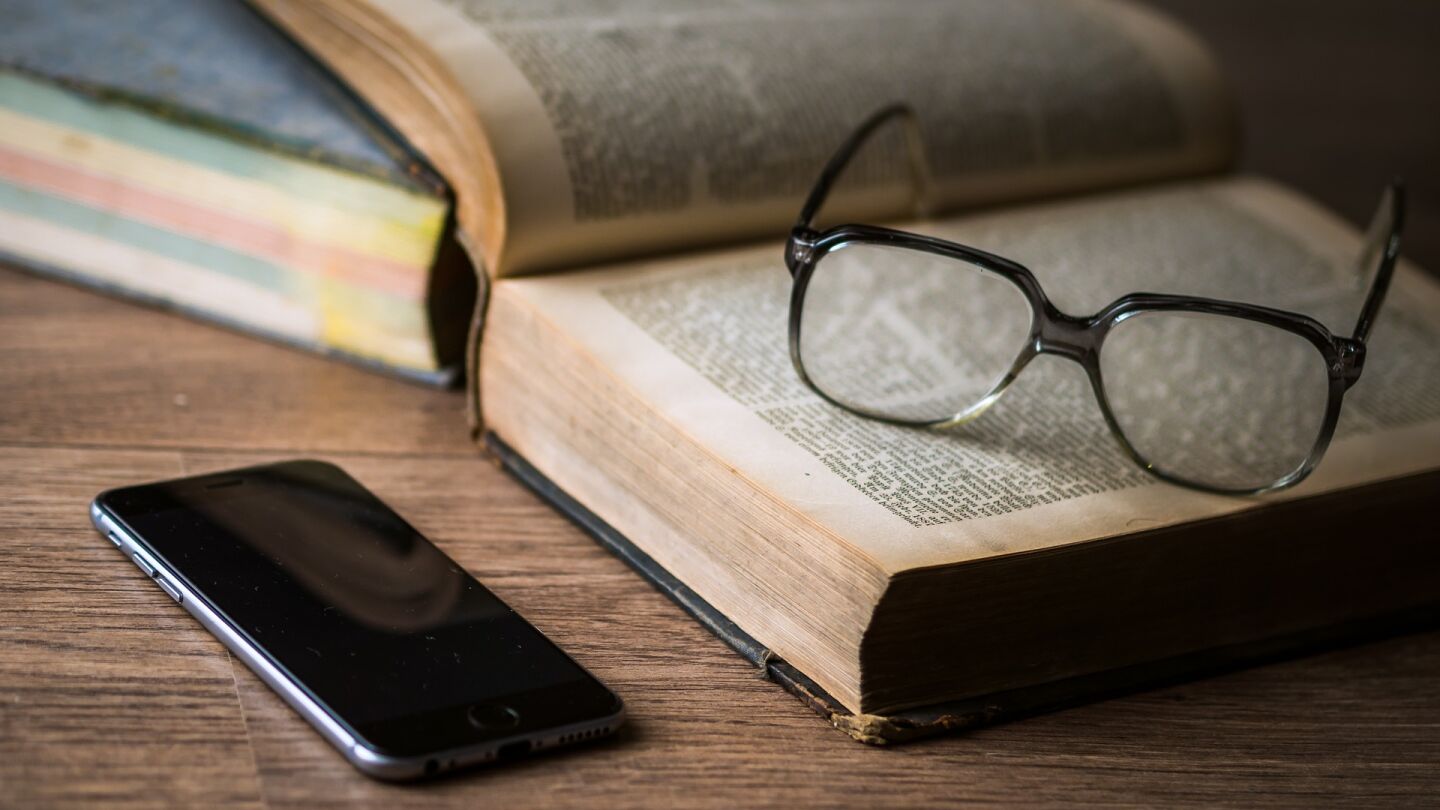 Imagen de un libro, unas gafas y un tel&eacute;fono m&oacute;vil