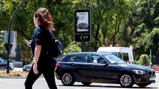 Una joven pasa junto a un termómetro que marca 35 grados centígrados Una joven pasa junto a un termómetro que marca 35 grados centígrados