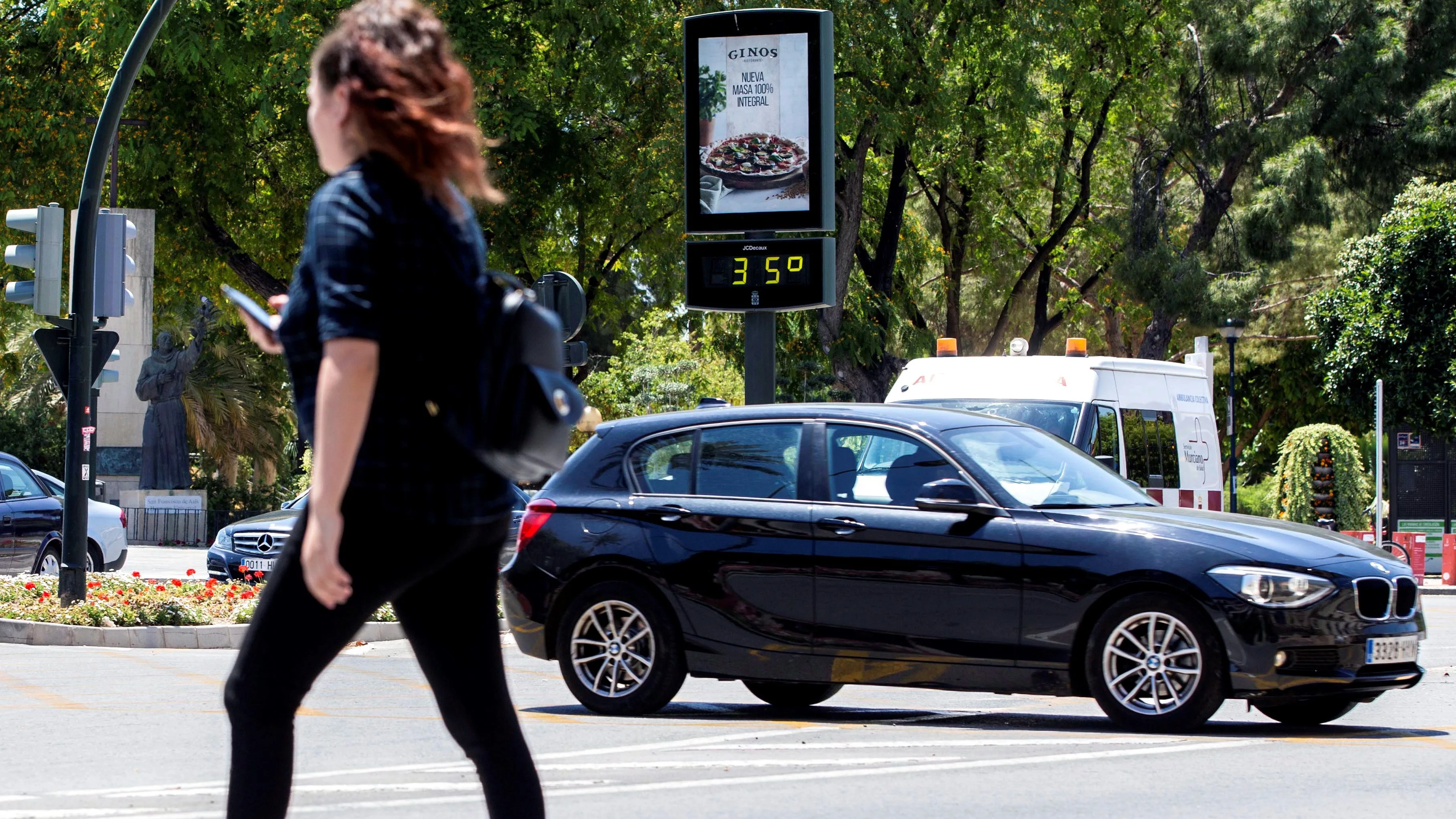 Una joven pasa junto a un termómetro que marca 35 grados centígrados