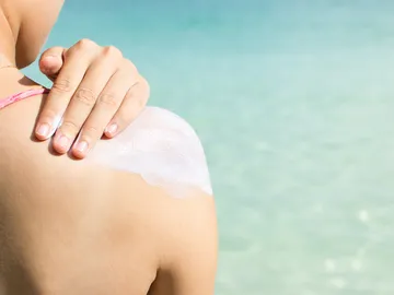 Una mujer se aplica crema solar Una mujer se aplica crema solar