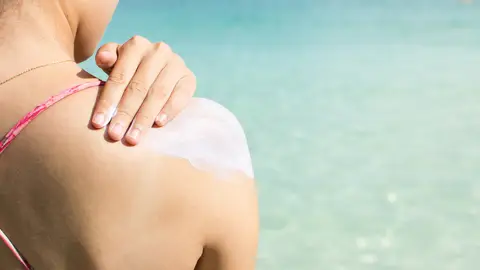 Una mujer se aplica crema solar Una mujer se aplica crema solar