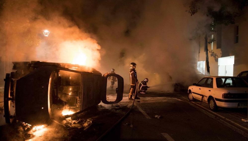Los bomberos tratan de apagar el fuego de un coche incendiado en el barrio de Malakoff , en Nantes