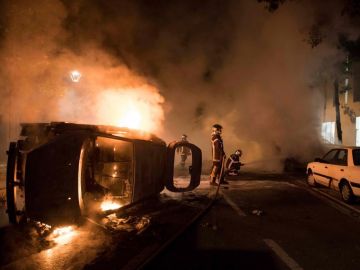 Los bomberos tratan de apagar el fuego de un coche incendiado en el barrio de Malakoff , en Nantes Los bomberos tratan de apagar el fuego de un coche incendiado en el barrio de Malakoff , en Nantes