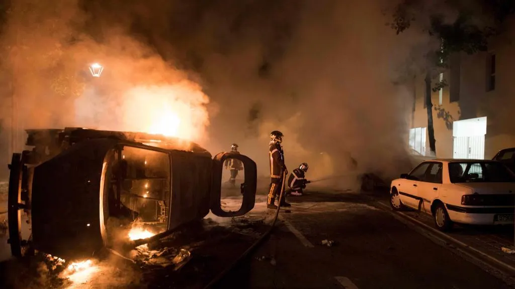 Los bomberos tratan de apagar el fuego de un coche incendiado en el barrio de Malakoff , en Nantes