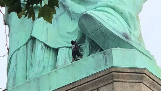 Una mujer escala la estatua de la libertad Una mujer escala la estatua de la libertad