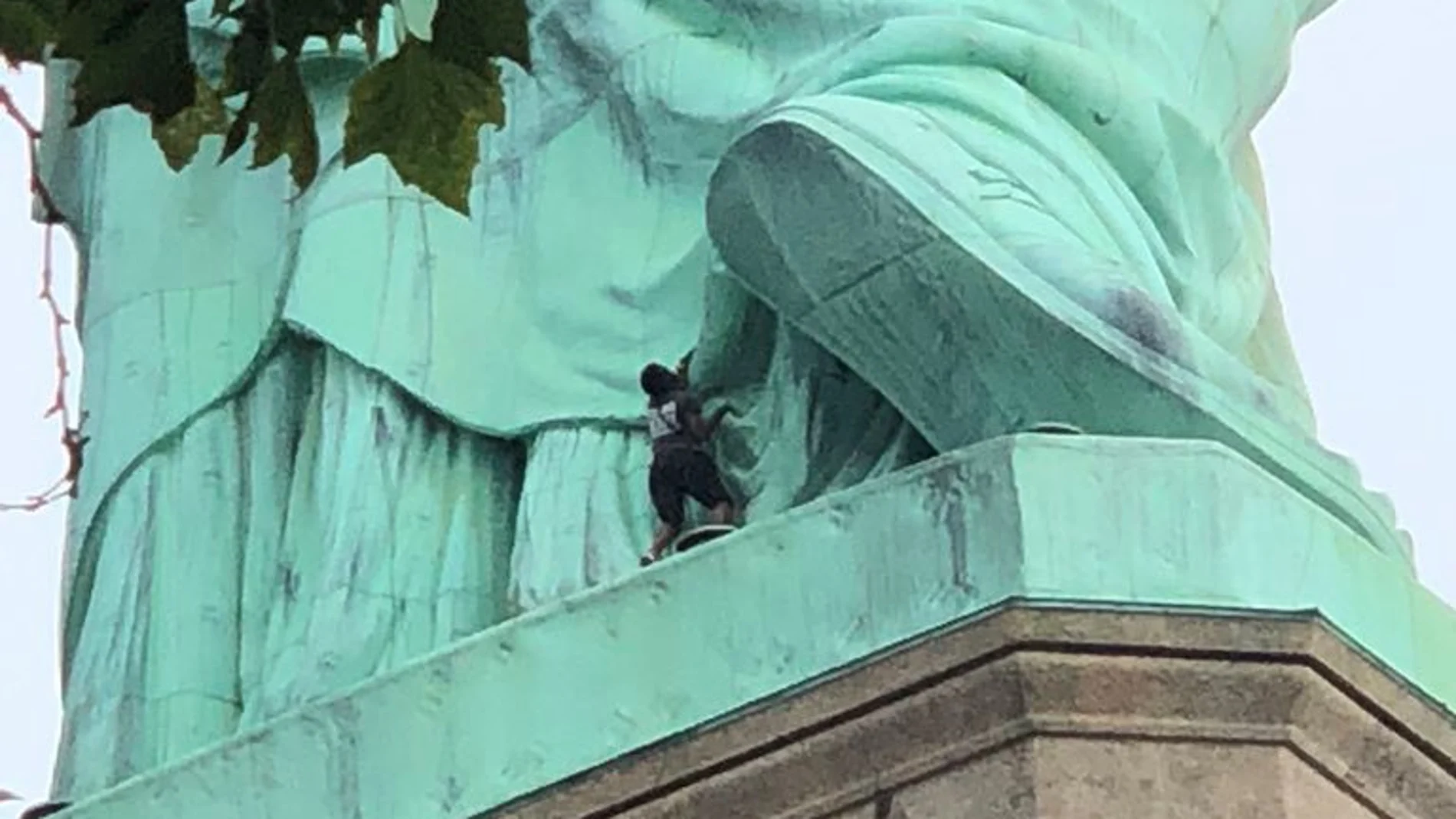 Una mujer escala la estatua de la libertad