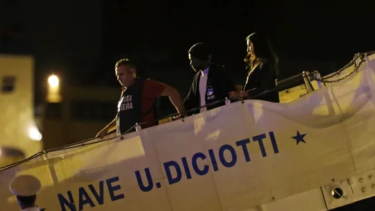 Guardias costeros escoltan a dos migrantes que desembarcan del Diciotti en el puerto de Trapani Guardias costeros escoltan a dos migrantes que desembarcan del Diciotti en el puerto de Trapani