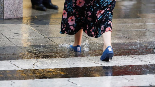 Imagen de una mujer cruzando bajo fuertes lluvias Imagen de una mujer cruzando bajo fuertes lluvias