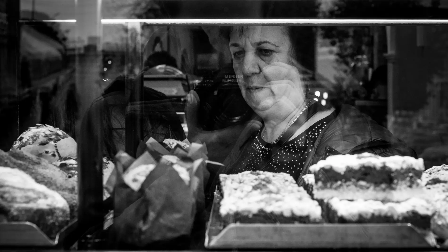 Mujer mayor mirando una vitrina con pasteles. Imagen: Pxhere.com