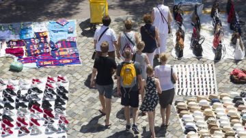 Unos turistas pasean por Las Ramblas de Barcelona entre varios manteros