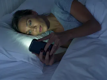Una mujer mira el móvil antes de dormir Una mujer mira el móvil antes de dormir