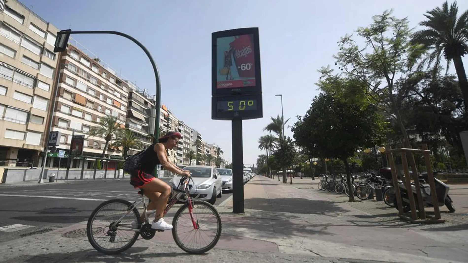 Un ciclista pasa junto a un termómetro que marca 50 grados en Córdoba, en una jornada marcada por la ola de calor que afecta a toda la Península