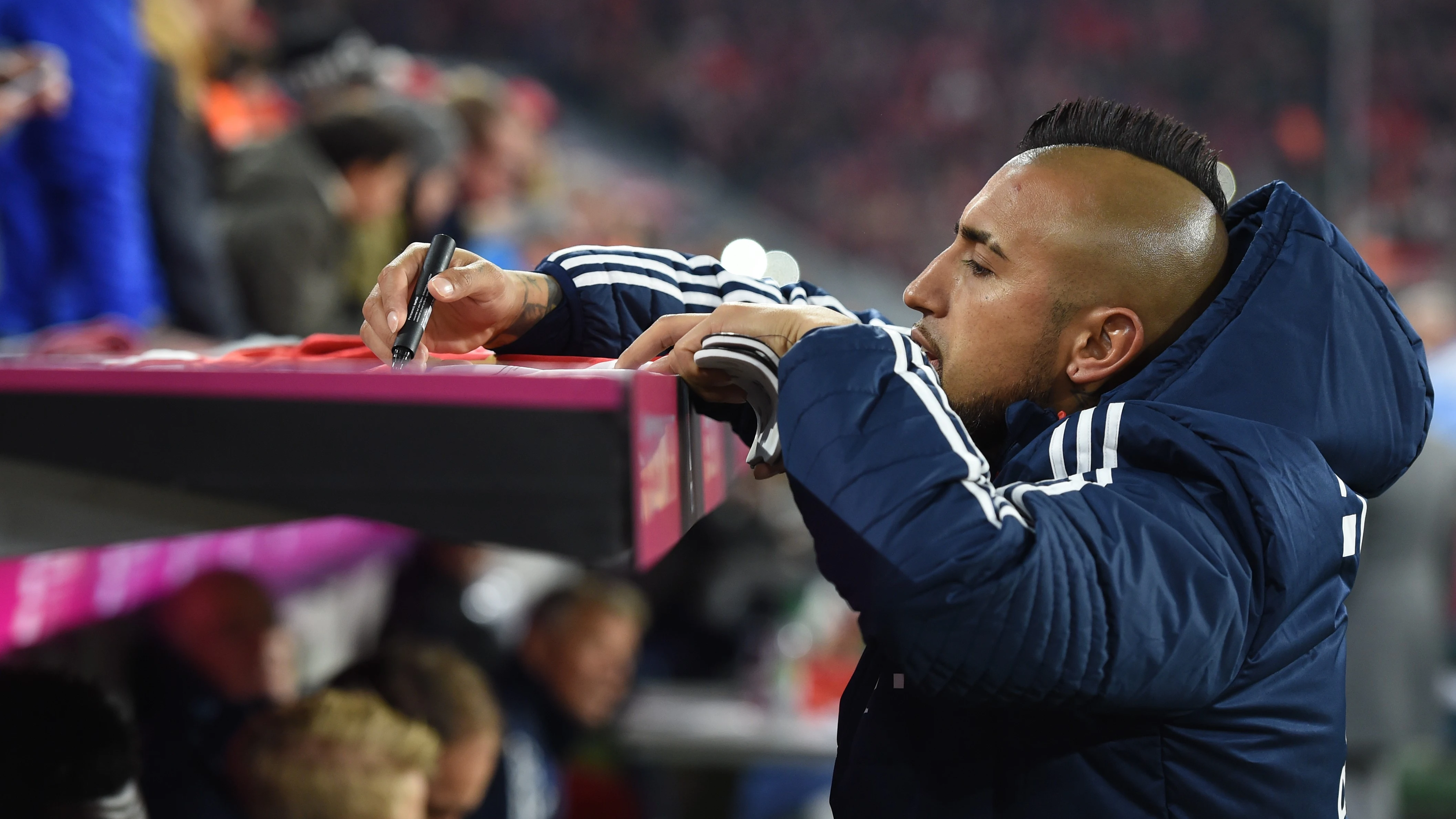 Arturo Vidal firma la camiseta de un aficionado en un partido del Bayern