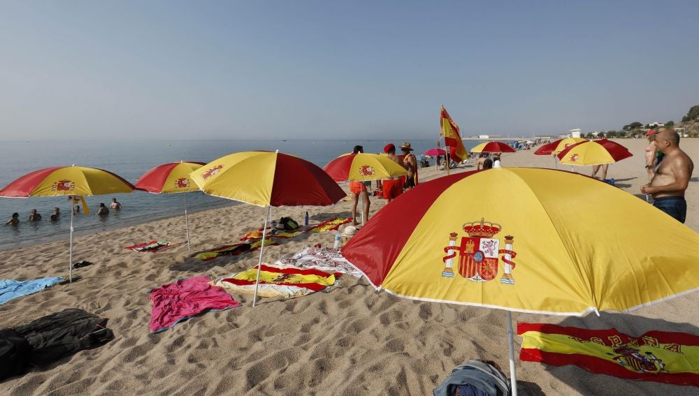 Una quincena de personas ha plantado una decena de sombrillas con los colores de la bandera de España.
