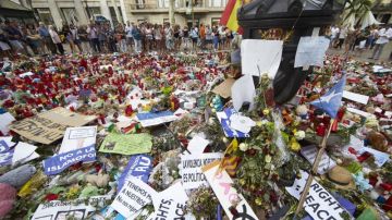 Ciudadanos y turistas observan un homenaje a las víctimas del 17A