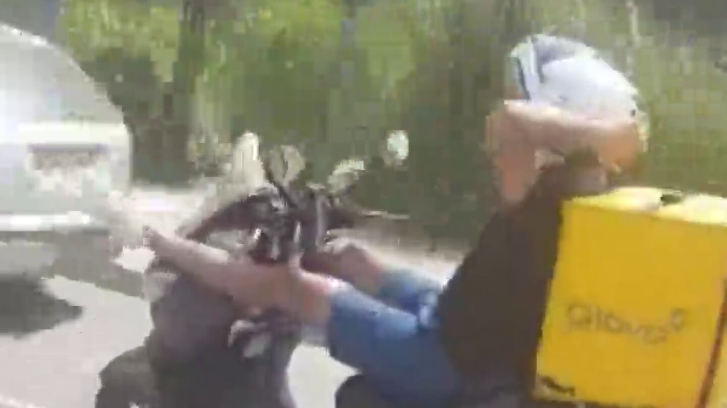 Con las manos detr&aacute;s de la cabeza y las piernas sobre el manillar: la temeraria acci&oacute;n de un repartidor mientras otro hombre le graba