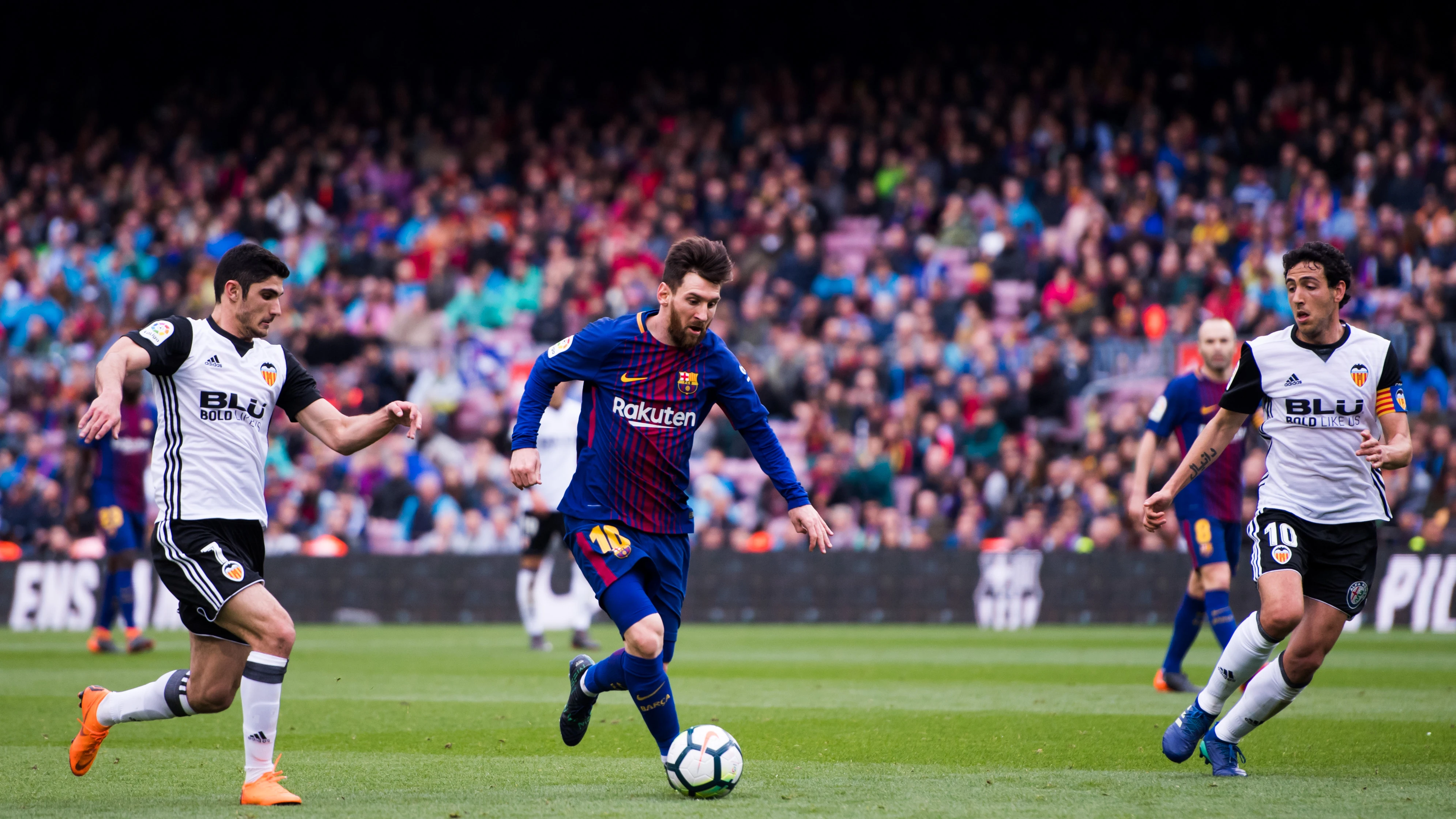 Guedes y Parejo intentan arrebatar el balón a Messi