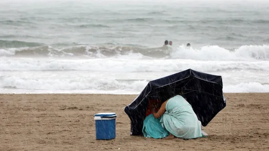 Una mujer se protege de la lluvia con su sombrilla en la playa de la Malvarrosa bajo la lluvia Una mujer se protege de la lluvia con su sombrilla en la playa de la Malvarrosa bajo la lluvia