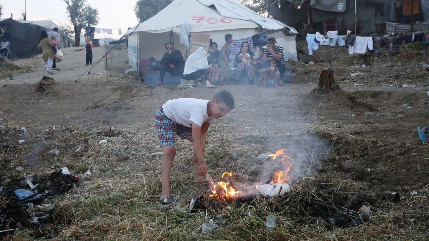 Un ni&ntilde;o hace un fuego en el campamento de refugiados de Moria, en la isla de Lesbos (Grecia)