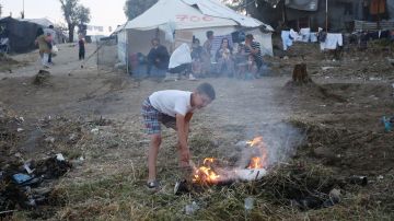 Un niño hace un fuego en el campamento de refugiados de Moria, en la isla de Lesbos (Grecia)