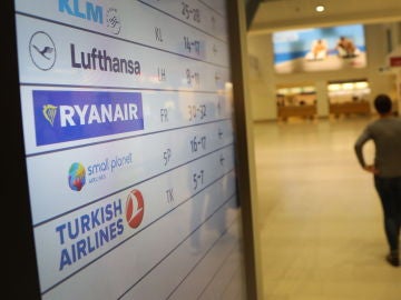 Pasajeros caminan frente a una pantalla con el logo de la aerolínea de bajo coste irlandesa Ryanair Pasajeros caminan frente a una pantalla con el logo de la aerolínea de bajo coste irlandesa Ryanair