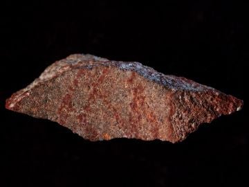 Lámina de roca con líneas pintadas color rojo