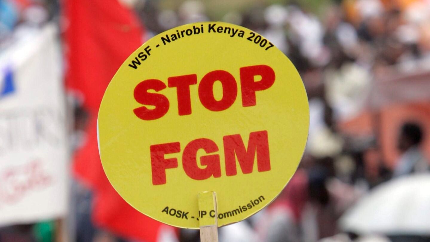 Una mujer levanta una pancarta en la que dice "Poned fin a la mutilaci&oacute;n genital femenina (FGM)' durante una gran manifestaci&oacute;n, desde Kibera, el mayor barrio marginal de &Aacute;frica en Nairobi, Kenia