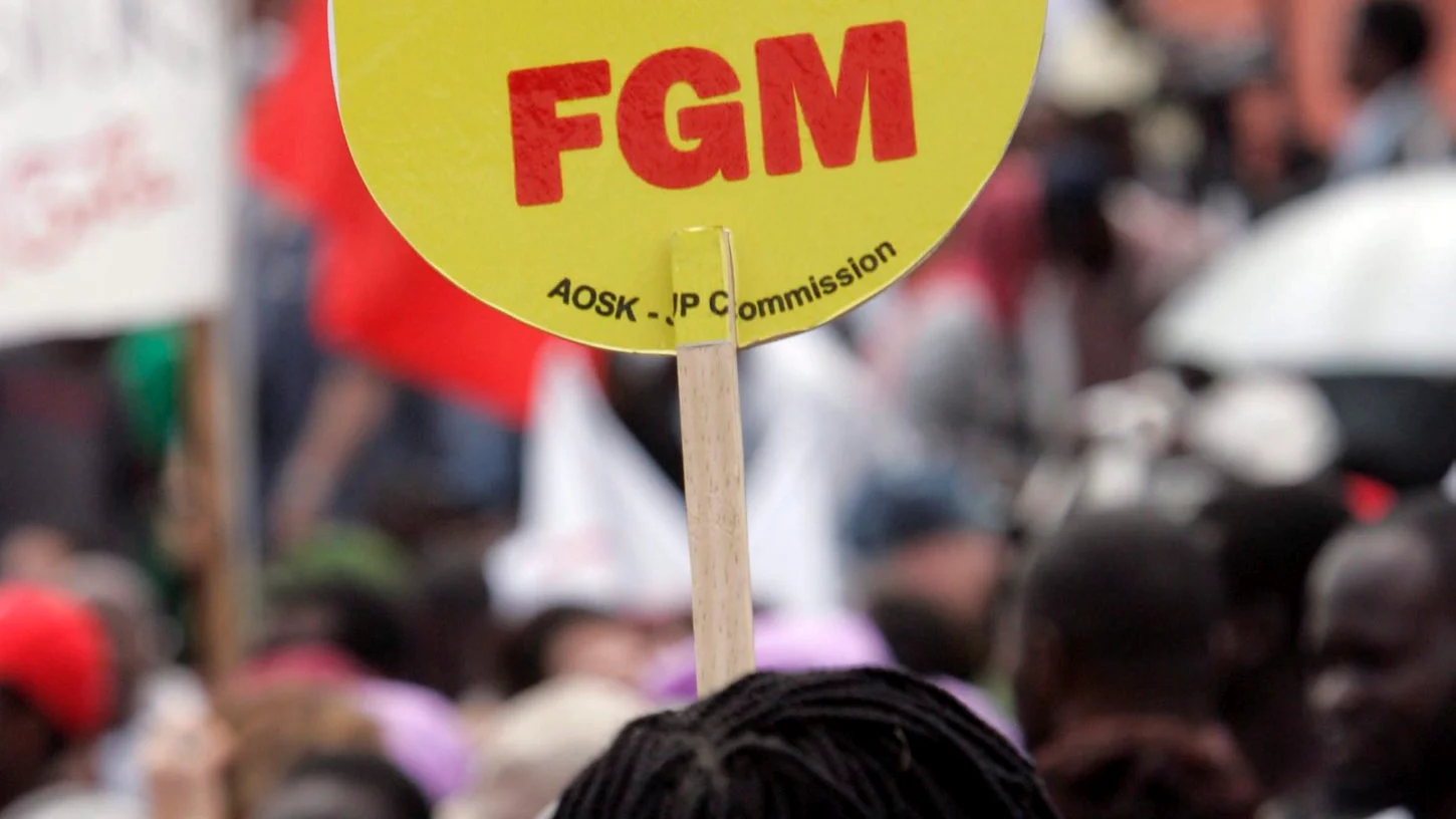 Una mujer levanta una pancarta en la que dice "Poned fin a la mutilación genital femenina (FGM)' durante una gran manifestación, desde Kibera, el mayor barrio marginal de África en Nairobi, Kenia