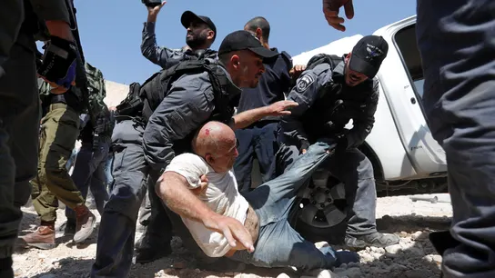 Soldados israelíes detienen a un palestino mientras los manifestantes bloquean el paso a una excavadora del ejército israelí Soldados israelíes detienen a un palestino mientras los manifestantes bloquean el paso a una excavadora del ejército israelí