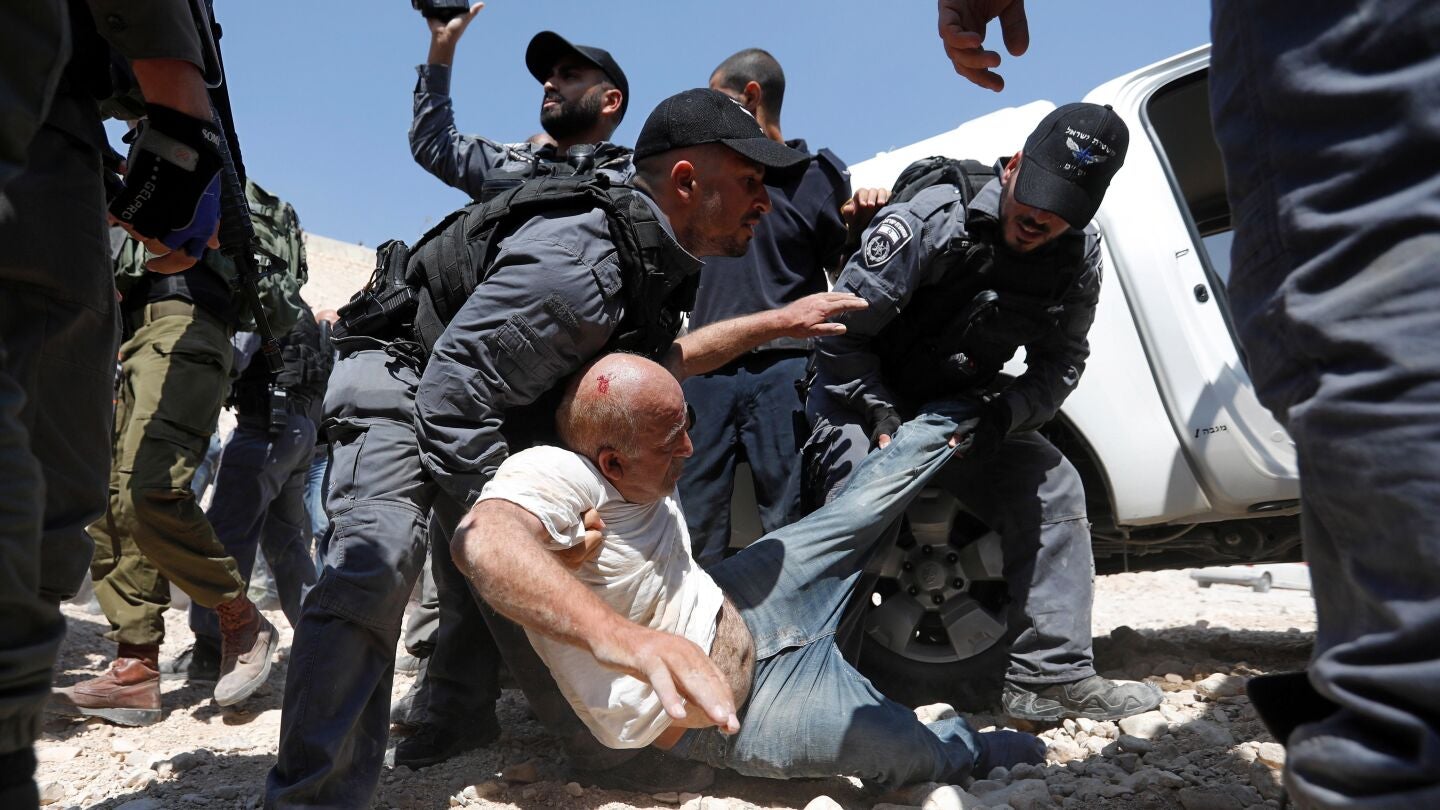 Soldados israel&iacute;es detienen a un palestino mientras los manifestantes bloquean el paso a una excavadora del ej&eacute;rcito israel&iacute; 