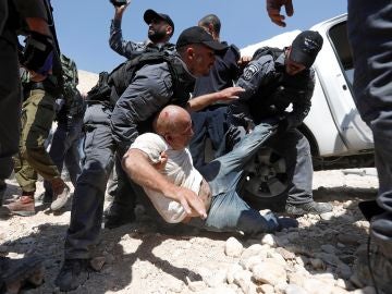 Soldados israelíes detienen a un palestino mientras los manifestantes bloquean el paso a una excavadora del ejército israelí Soldados israelíes detienen a un palestino mientras los manifestantes bloquean el paso a una excavadora del ejército israelí