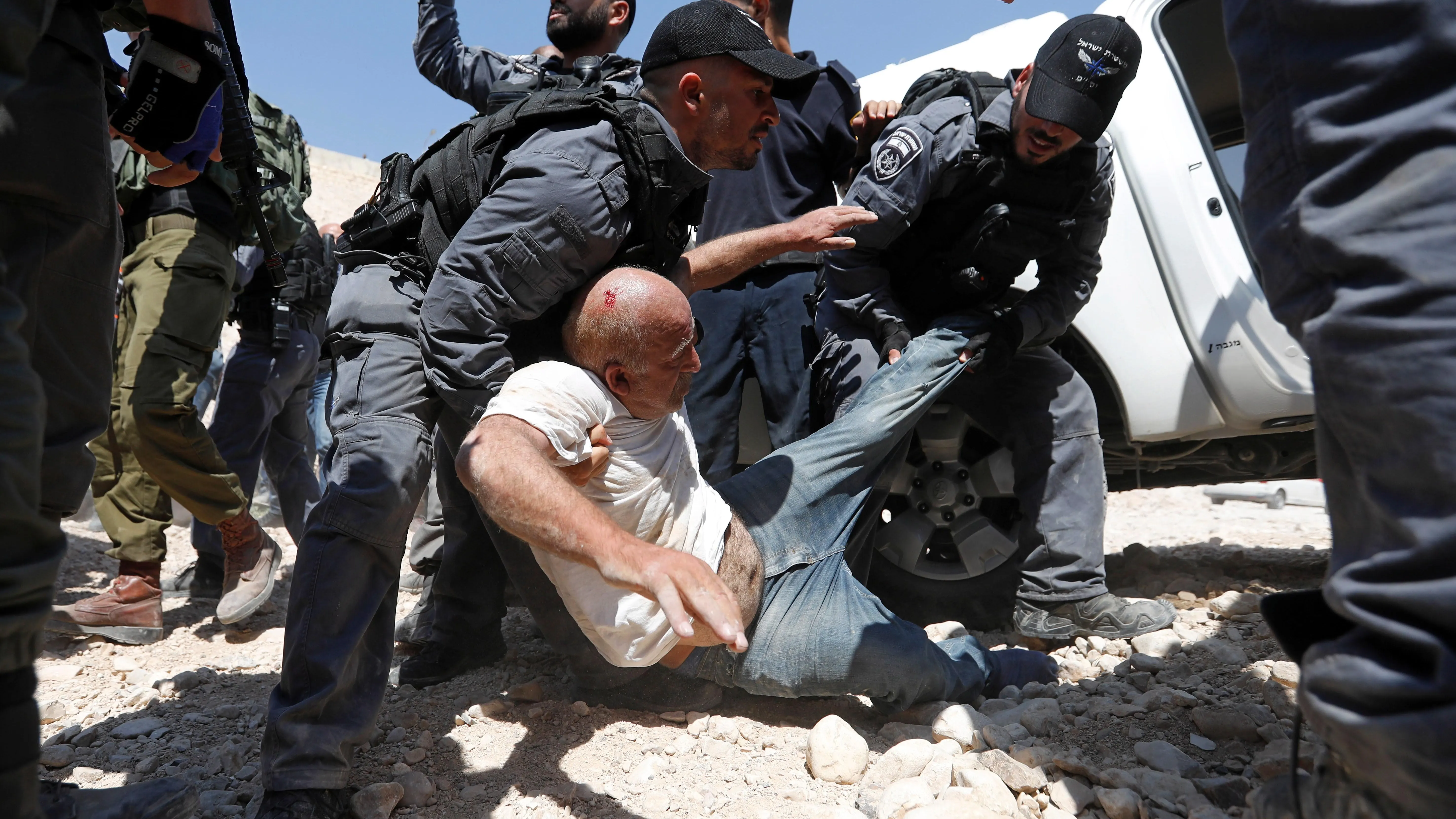 Soldados israelíes detienen a un palestino mientras los manifestantes bloquean el paso a una excavadora del ejército israelí 