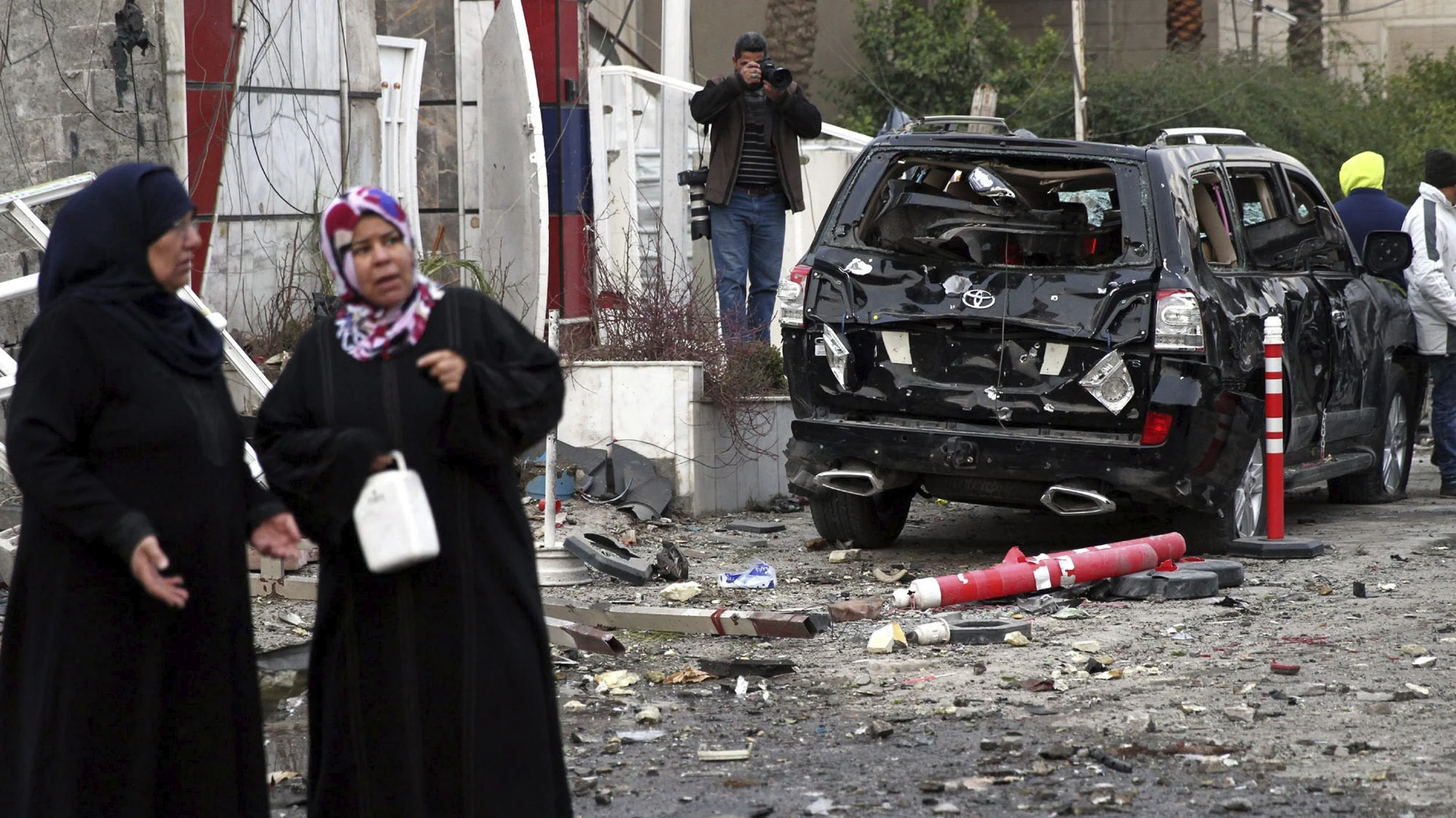 Un grupo de personas permanece en el lugar donde explotó un coche bomba, en Bagdad, Irak