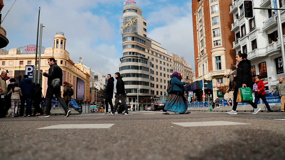 Viandantes cruzan la Gran vía de Madrid a la altura de la plaza de Callao