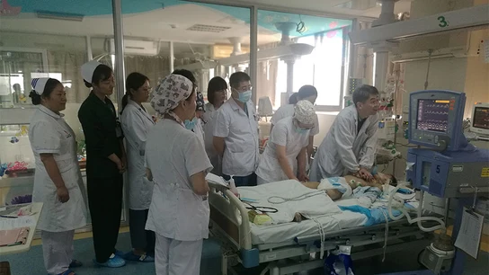 Imagen de los médicos chinos junto a la cama del niño Imagen de los médicos chinos junto a la cama del niño