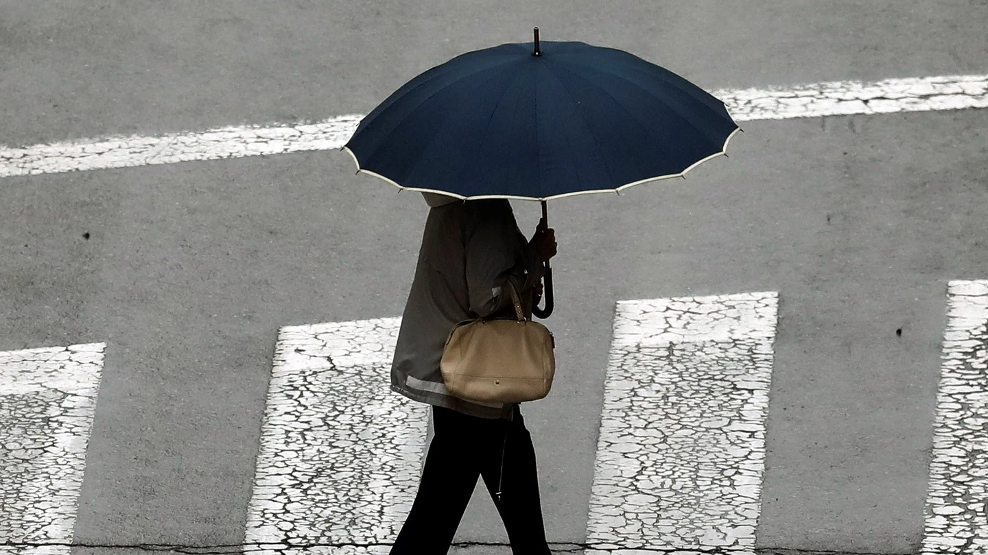 Una mujer se protege con un paraguas ante la lluvia Una mujer se protege con un paraguas ante la lluvia