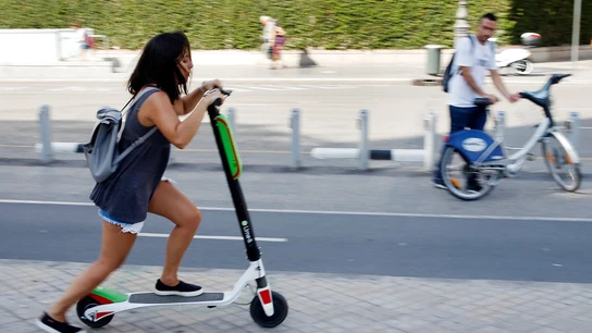 Una joven circulando en un patinete eléctrico Una joven circulando en un patinete eléctrico