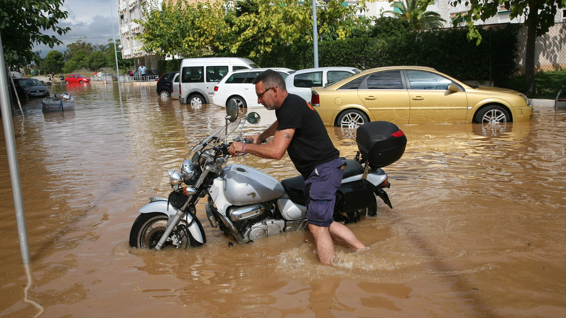 Un vecino intenta mover una motocicleta en el barrio de la Pineda de Vila-Seca (Tarragona)