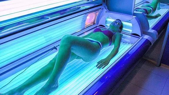 Una joven se somete a una sesión en una cabina de bronceado