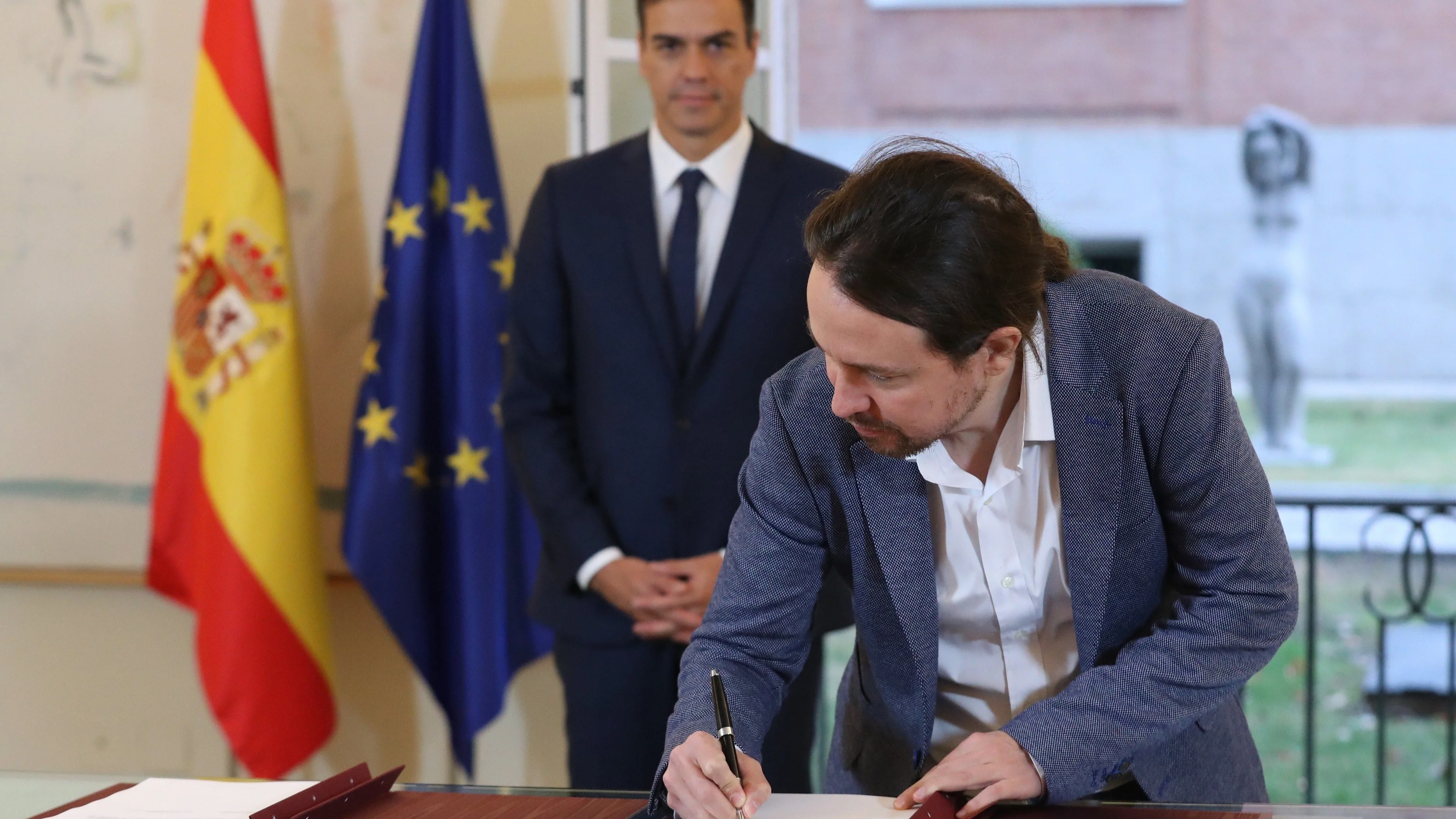 El secretario general de Podemos, Pablo Iglesias, firmando el acuerdo presupuestario