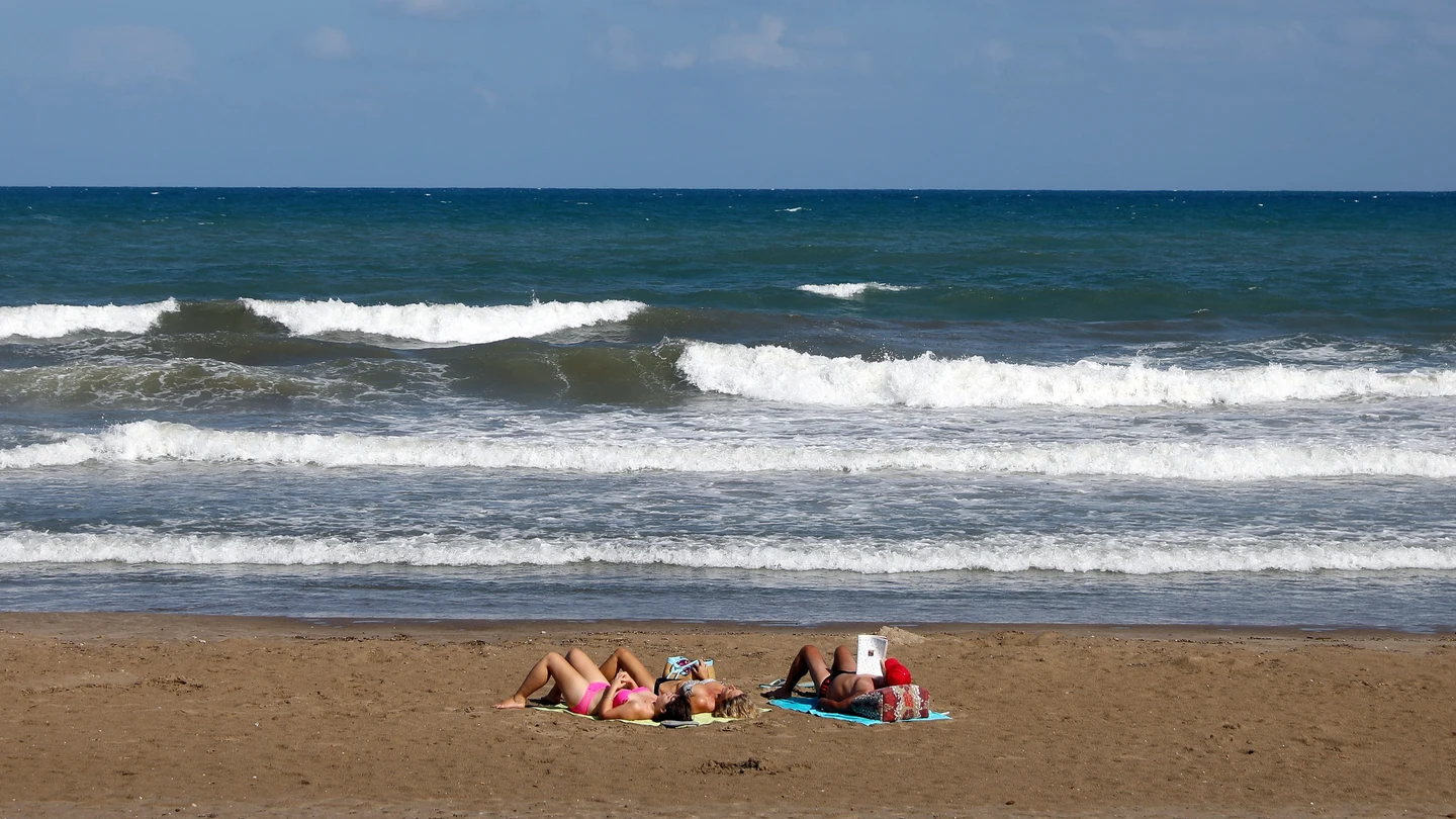 Tres personas toman el sol, el pasado mes de septiembre en la playa de la Malvarrosa de Valencia Tres personas toman el sol, el pasado mes de septiembre en la playa de la Malvarrosa de Valencia